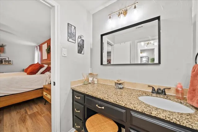 a en suite bathroom with a granite countertop double vanity sink and a mirror