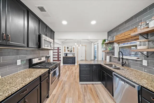 a kitchen with stainless steel appliances granite countertop a sink stove and cabinets