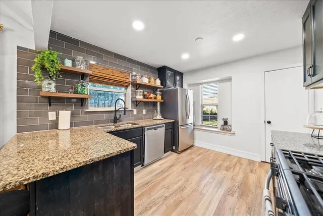 a kitchen with stainless steel appliances granite countertop sink stove and refrigerator