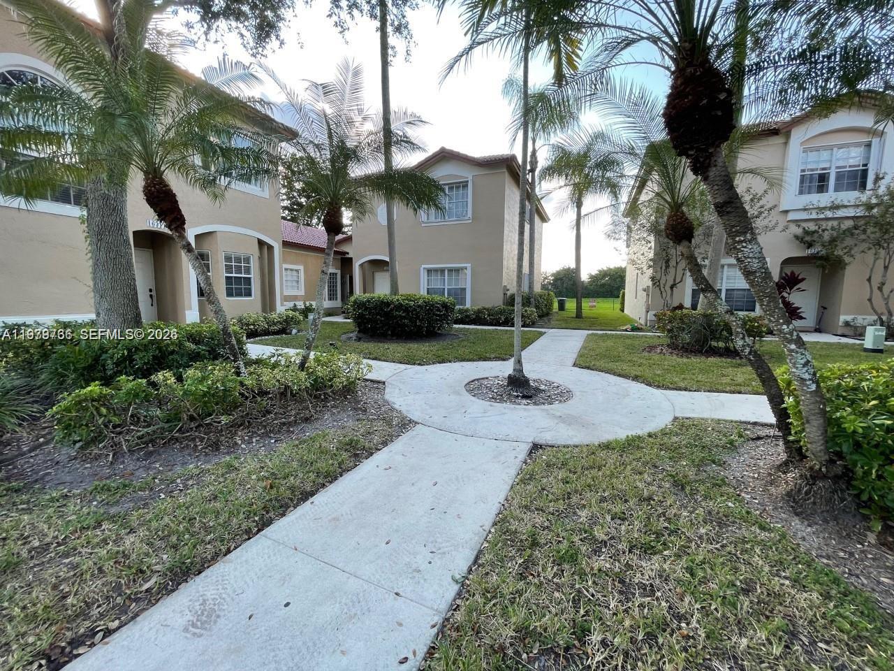 16309 Emerald Cove Road, Unit 16309 Weston, FL 33331 - Photo 1 of 41 a front view of a house with garden and trees