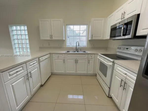 a kitchen with cabinets appliances a sink and a window