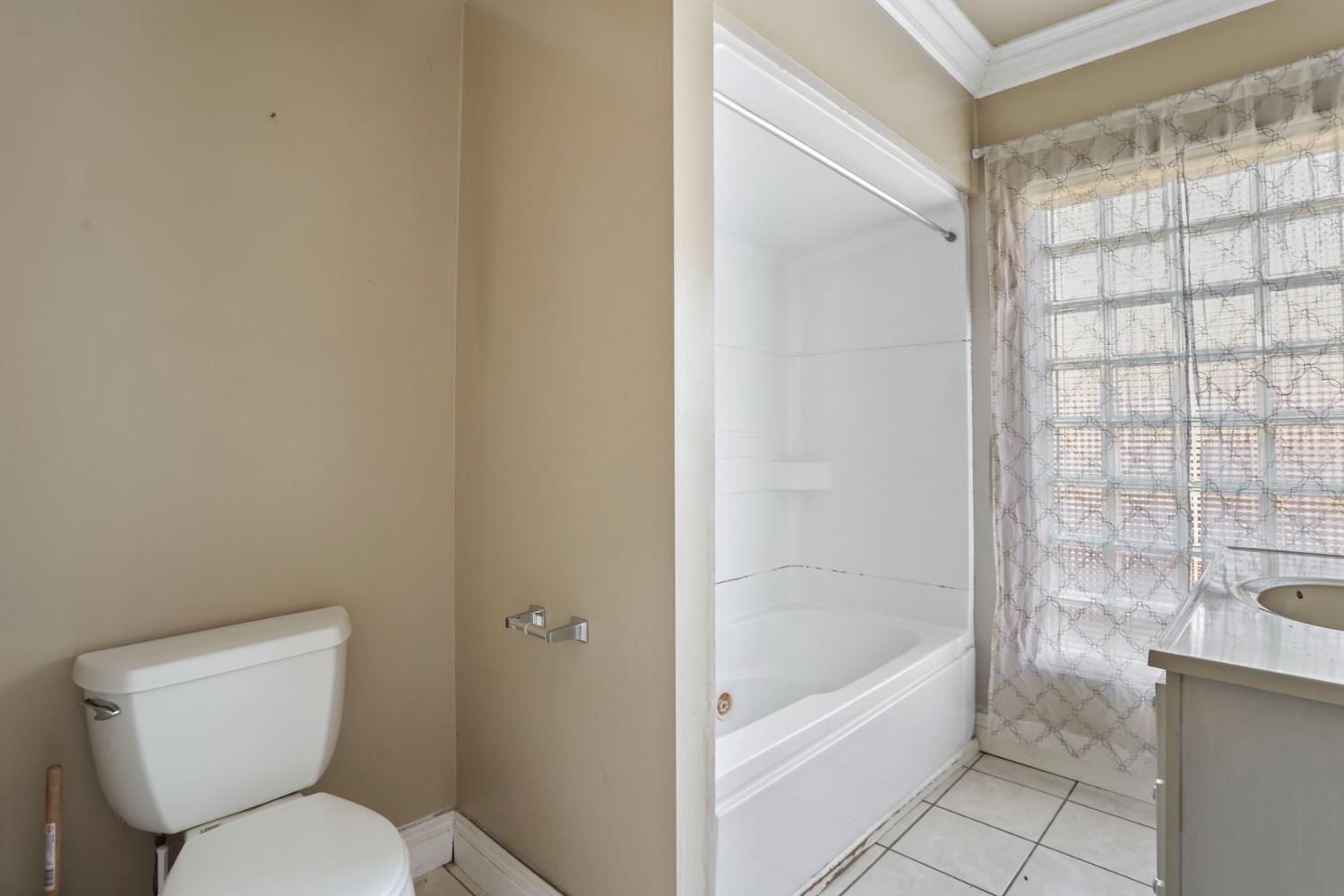 916 Elm Avenue Modesto, CA 95351 - Photo 23 of 52 24. Bathroom with tub and glass block window A full bathroom with natural light, tile flooring, and a glass block window that adds privacy without losing brightness.