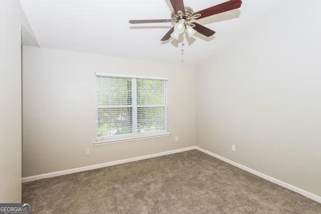 an empty room with a window and a fan