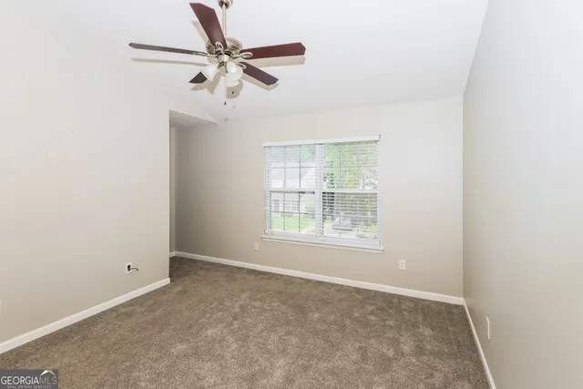 an empty room with a window and a fan
