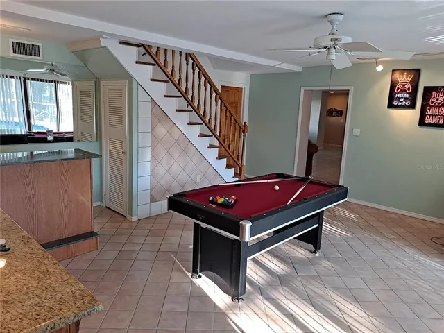 a room with wooden floor pool table and windows