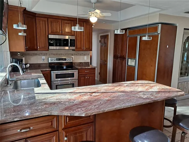 a kitchen with granite countertop a refrigerator stove and sink