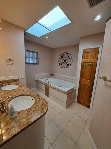 a bathroom with a granite countertop sink a mirror and a bathtub