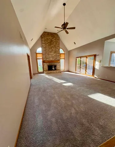 a view of an empty room with window and chandelier fan