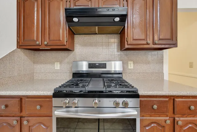 a kitchen with granite countertop stove and cabinets