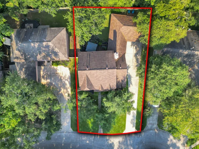 an aerial view of a house with a yard and a large tree