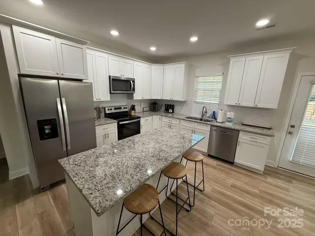 a kitchen with granite countertop a refrigerator stove microwave and cabinets
