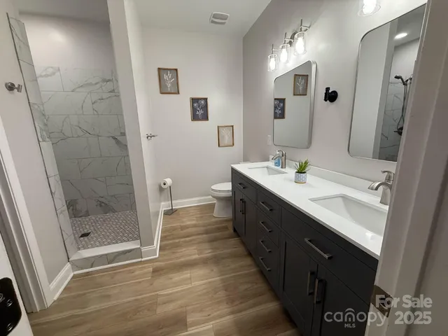 a spacious bathroom with a double vanity sink a toilet and a mirror