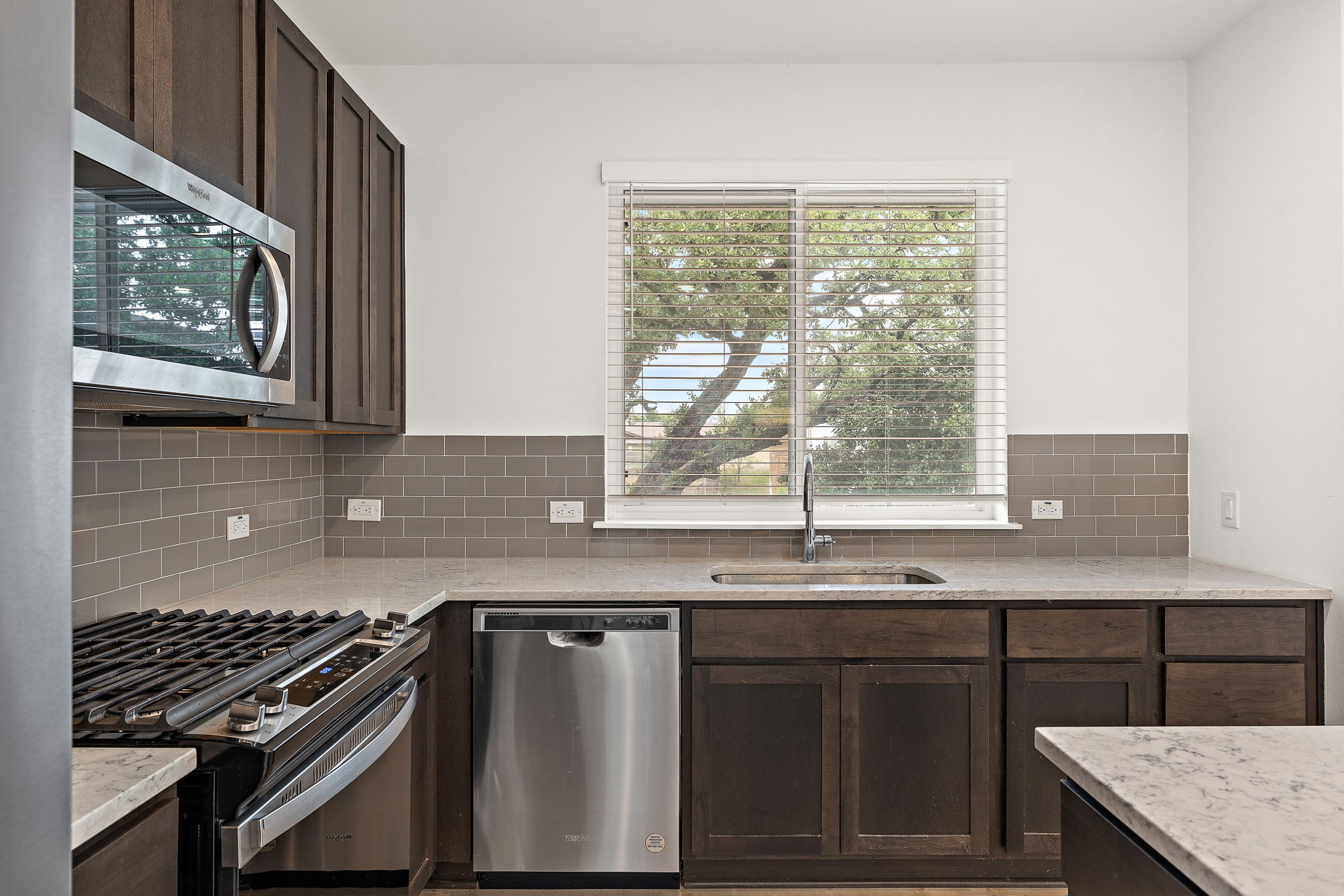 1206 Sarabeth Way Austin, TX 78721 - Photo 12 of 27 Kitchen with dark brown cabinetry, tasteful backsplash, stainless steel appliances, and a sink