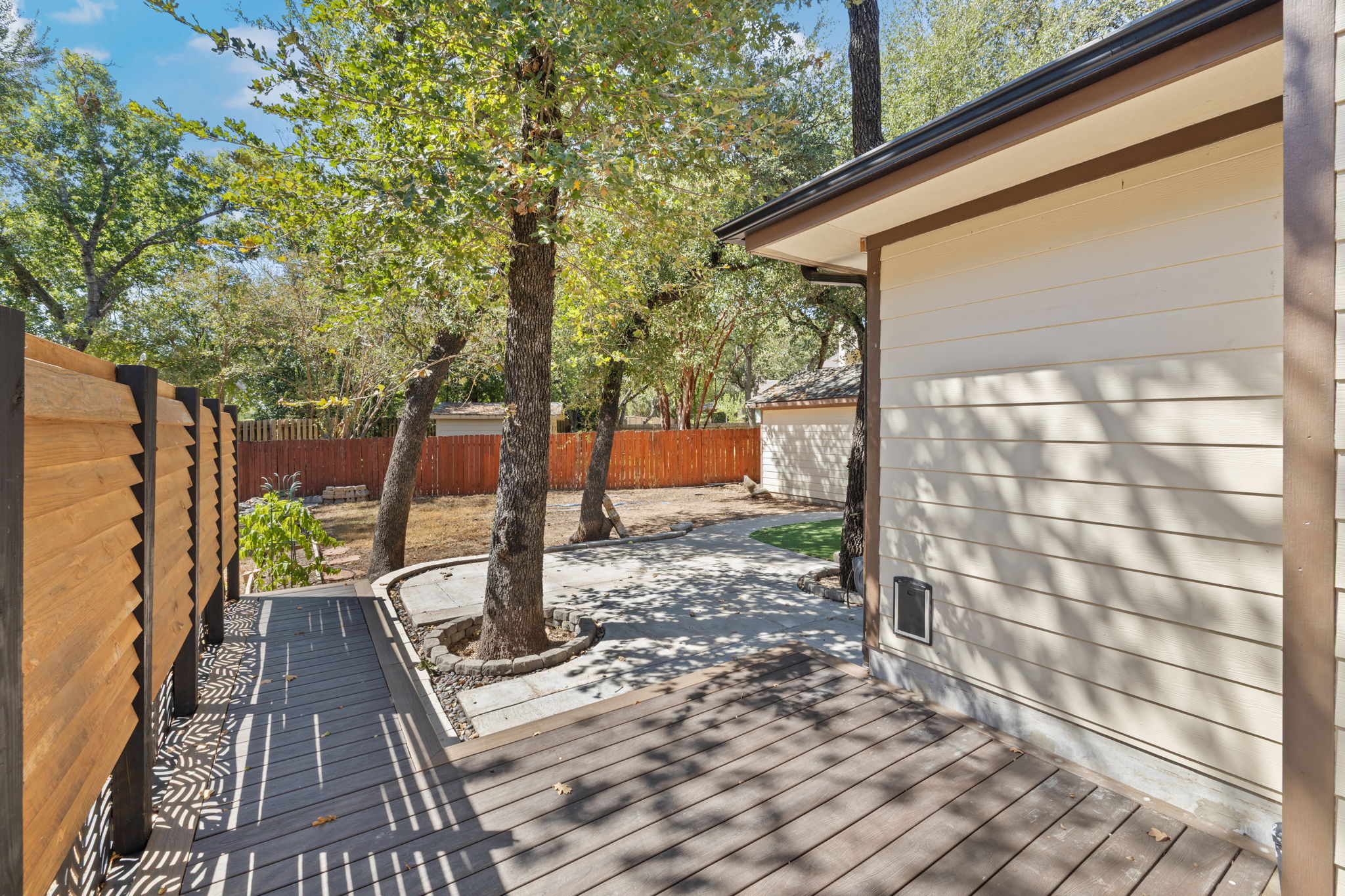 2211 Spring Hollow Path Round Rock, TX 78681 - Photo 34 of 36 Mature trees shade a spacious patio and deck area within the fenced backyard.