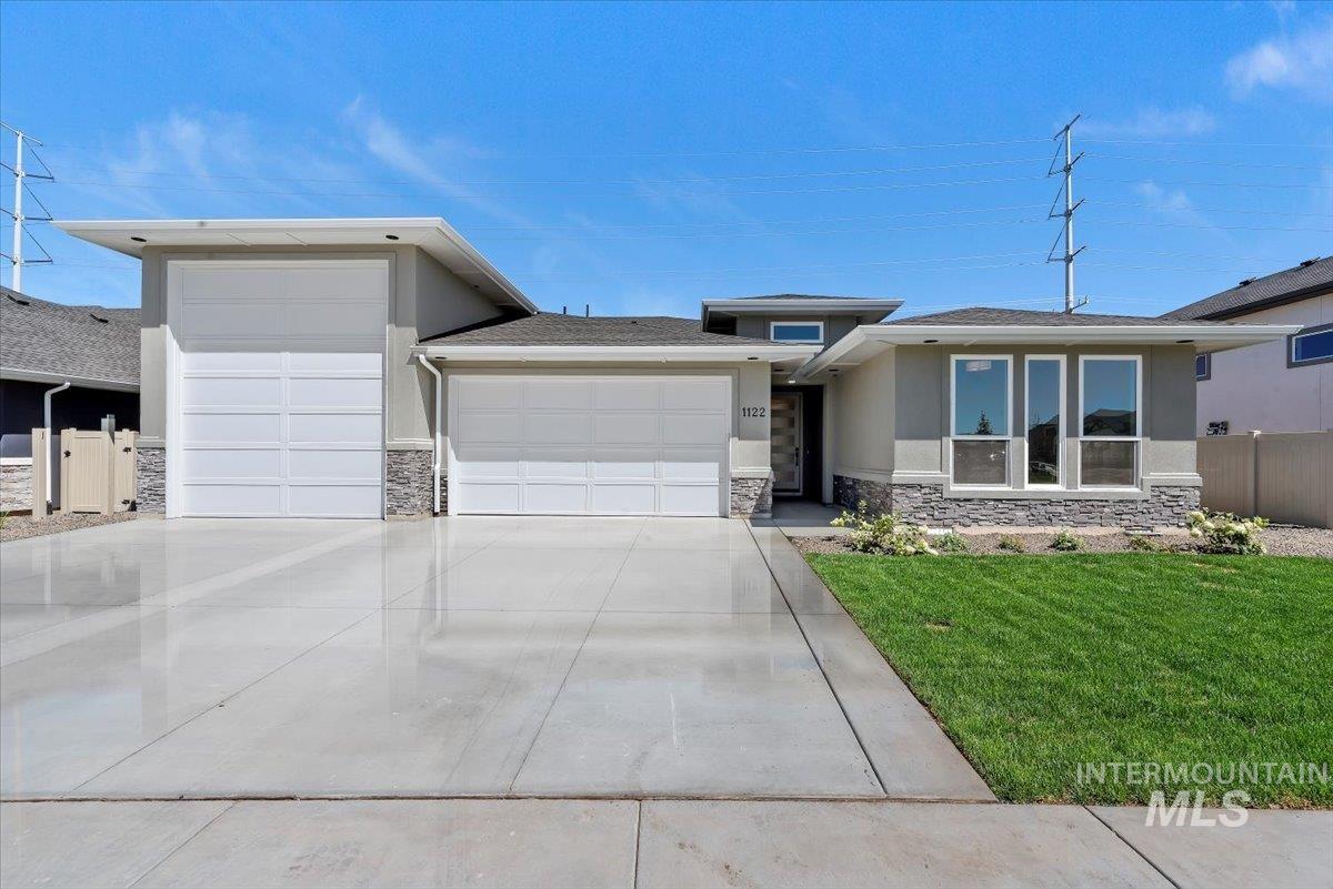 Prairie-style house with a garage, stucco siding, stone siding, and concrete driveway