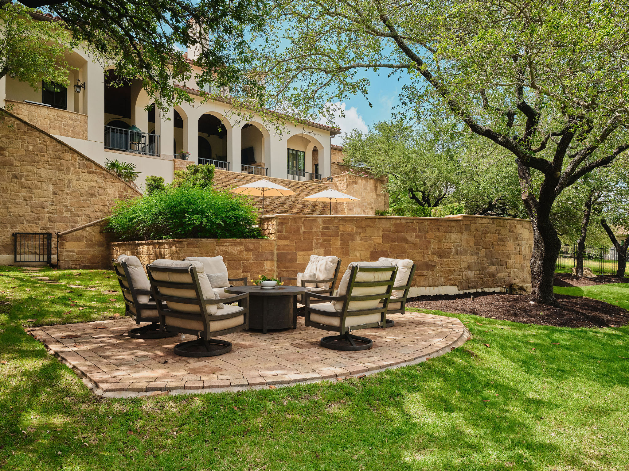 433 Brandon Way Austin, TX 78733 - Photo 36 of 40 An inviting stone patio with comfortable seating awaits outdoor gatherings amidst lush landscaping.