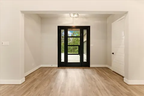 a view of an empty room with wooden floor and a window