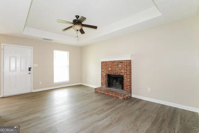 an empty room with wooden floor fireplace and windows