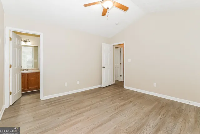 an empty room with wooden floor cabinet and windows