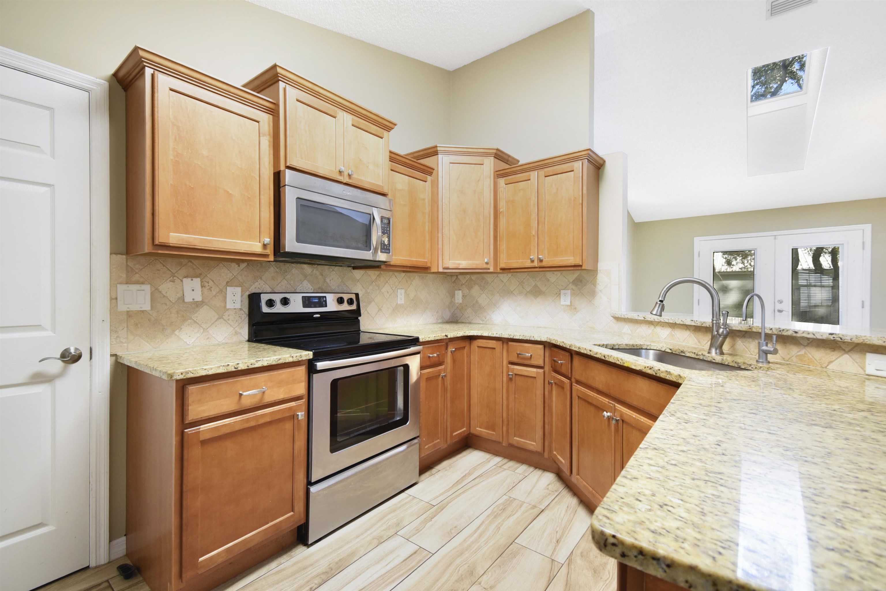317 Mystical Way St. Augustine, FL 32080 - Photo 11 of 25 Kitchen featuring appliances with stainless steel finishes, light stone counters, tasteful backsplash, and a peninsula