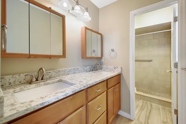 a bathroom with a granite countertop sink a mirror and a shower