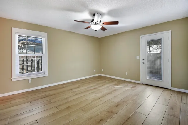 a view of an empty room with wooden floor and a window