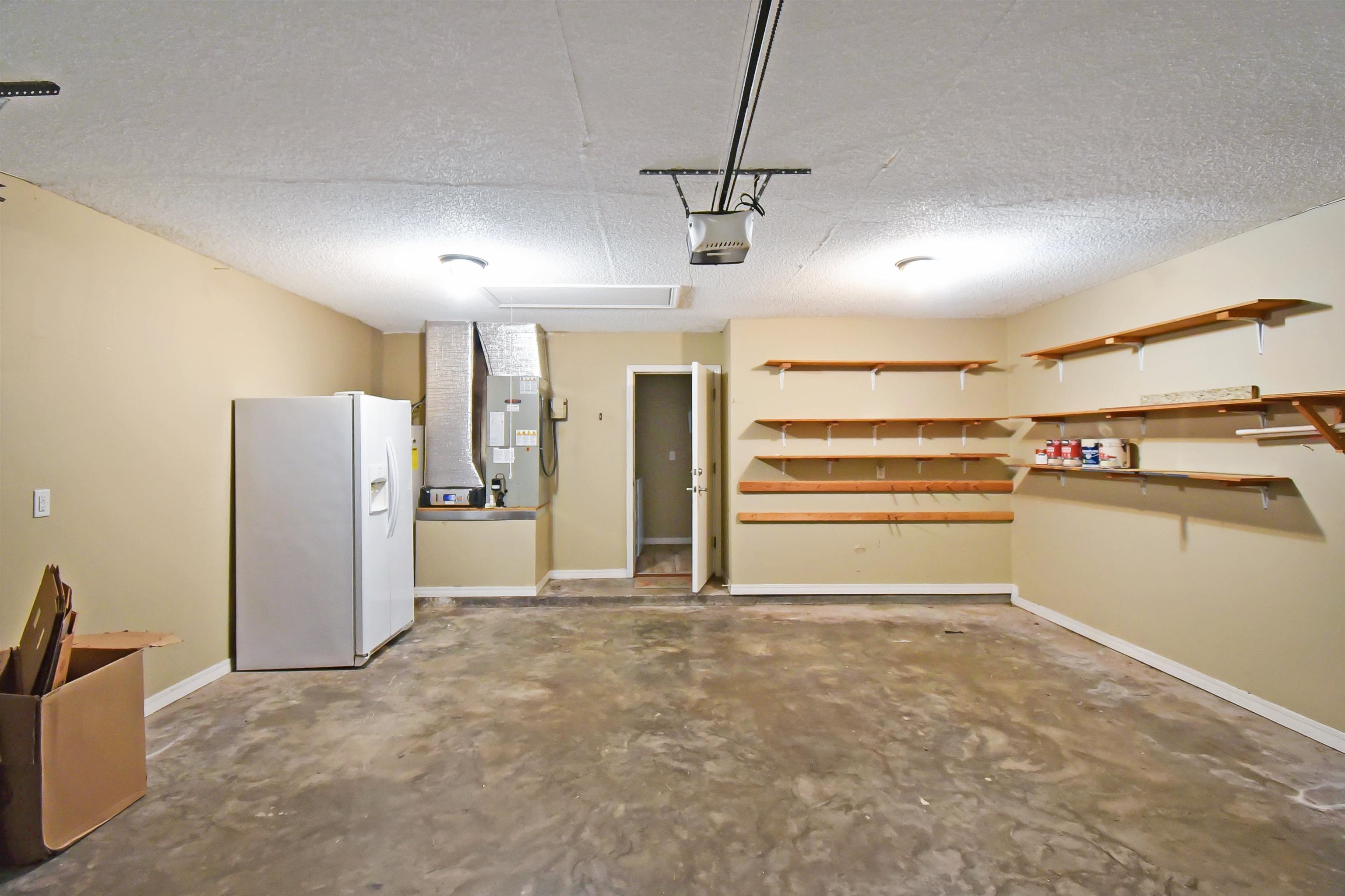 317 Mystical Way St. Augustine, FL 32080 - Photo 15 of 25 Garage featuring white fridge with ice dispenser, heating unit, and a garage door opener