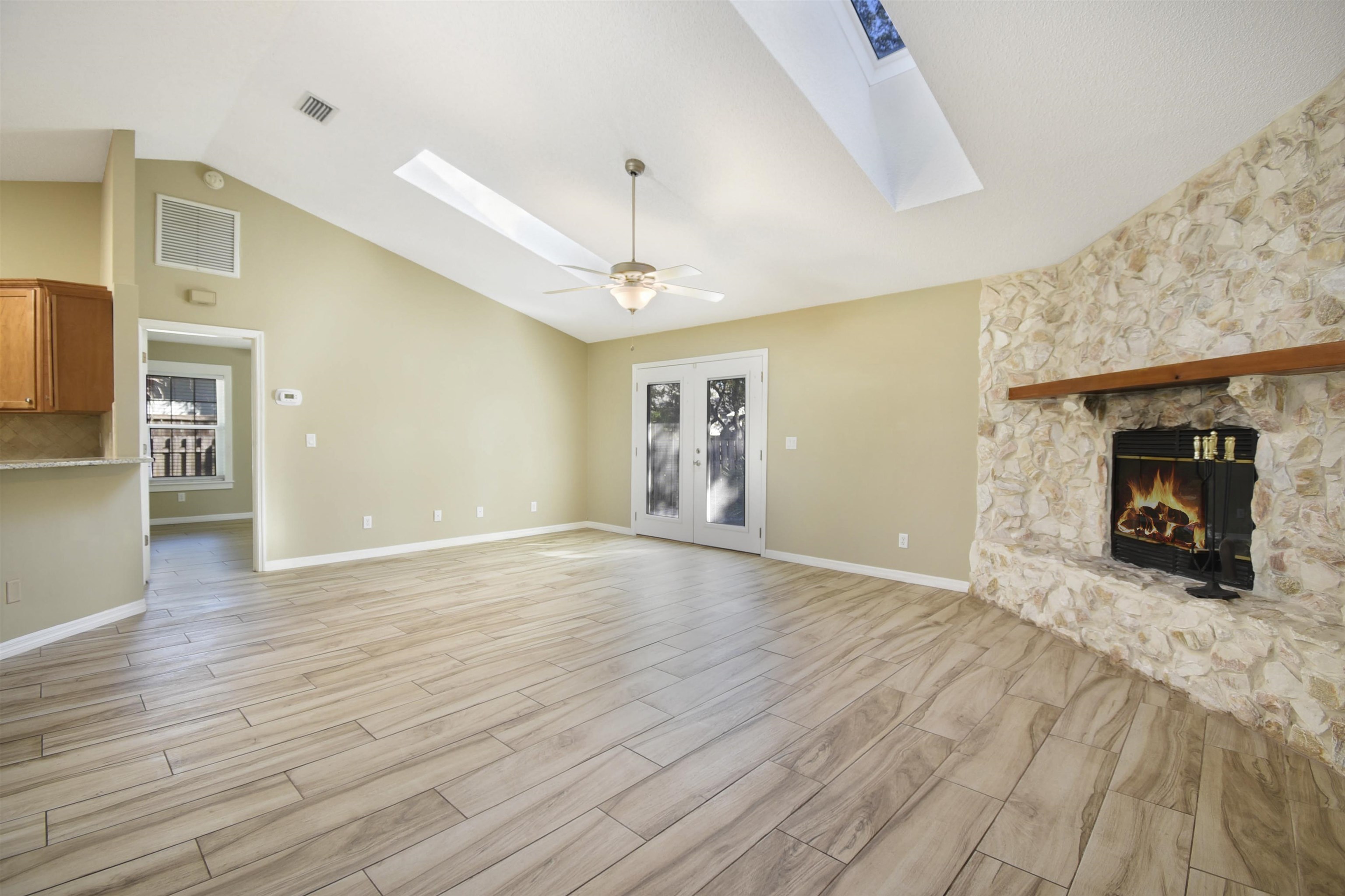 317 Mystical Way St. Augustine, FL 32080 - Photo 3 of 25 Unfurnished living room with a stone fireplace, ceiling fan, a skylight, wood finish floors, and high vaulted ceiling