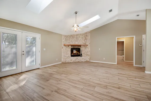 a view of an empty room with wooden floor fireplace and a window