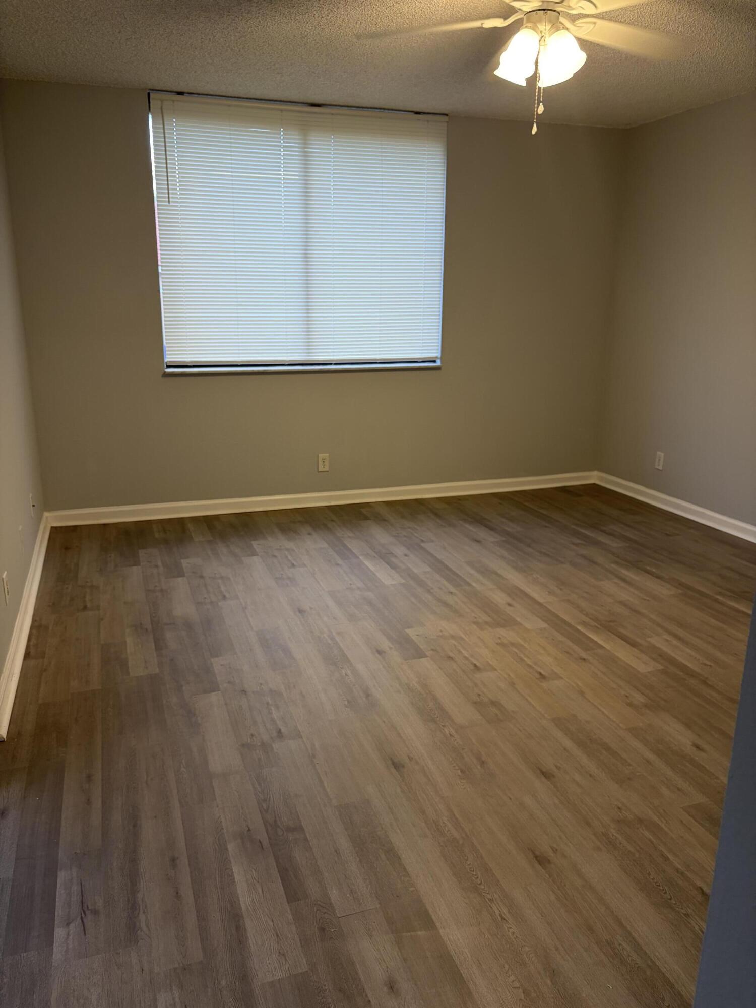8165 Severn Drive, Unit D Boca Raton, FL 33433 - Photo 9 of 14 a view of an empty room with wooden floor and a window