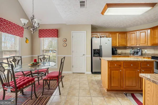 a kitchen with stainless steel appliances kitchen island granite countertop dining table chairs cabinets a sink and a window