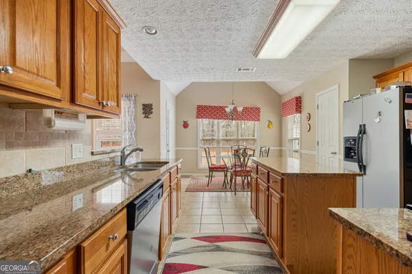 a kitchen with stainless steel appliances granite countertop a sink a stove and refrigerator