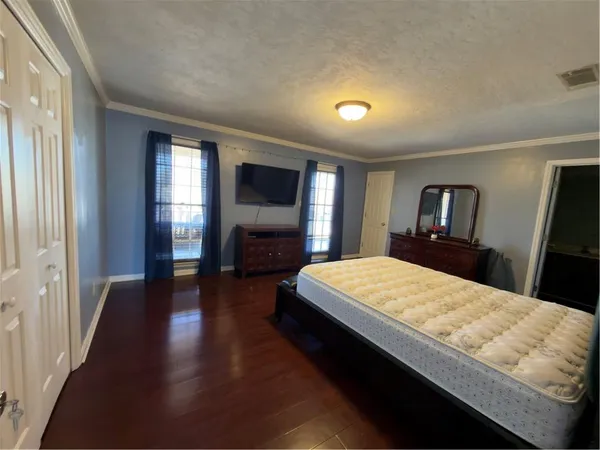 a large bedroom with wooden floor and bed