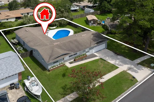 an aerial view of a house with a swimming pool and yard