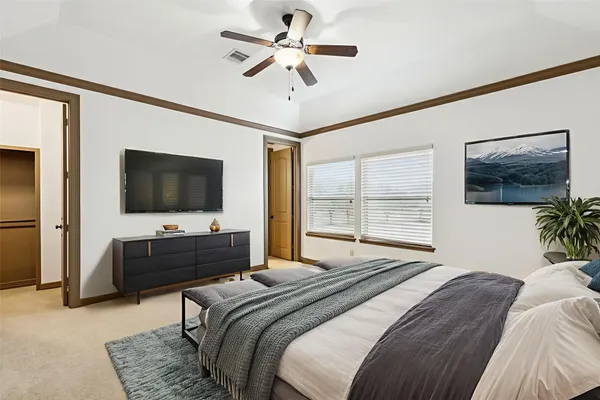 a bedroom with a bed television on desk and a window