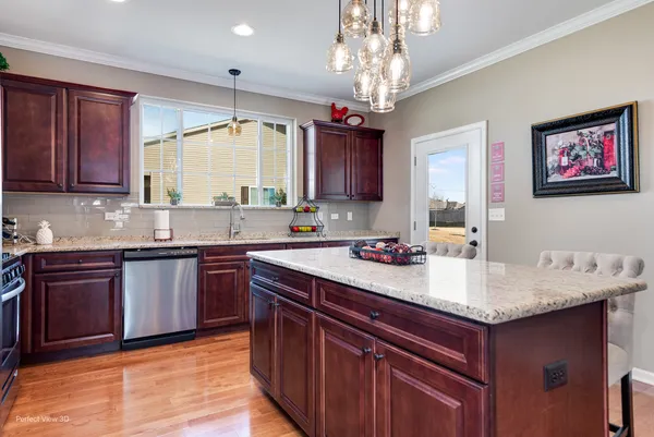 a kitchen with stainless steel appliances granite countertop a sink dishwasher stove and cabinets with wooden floor