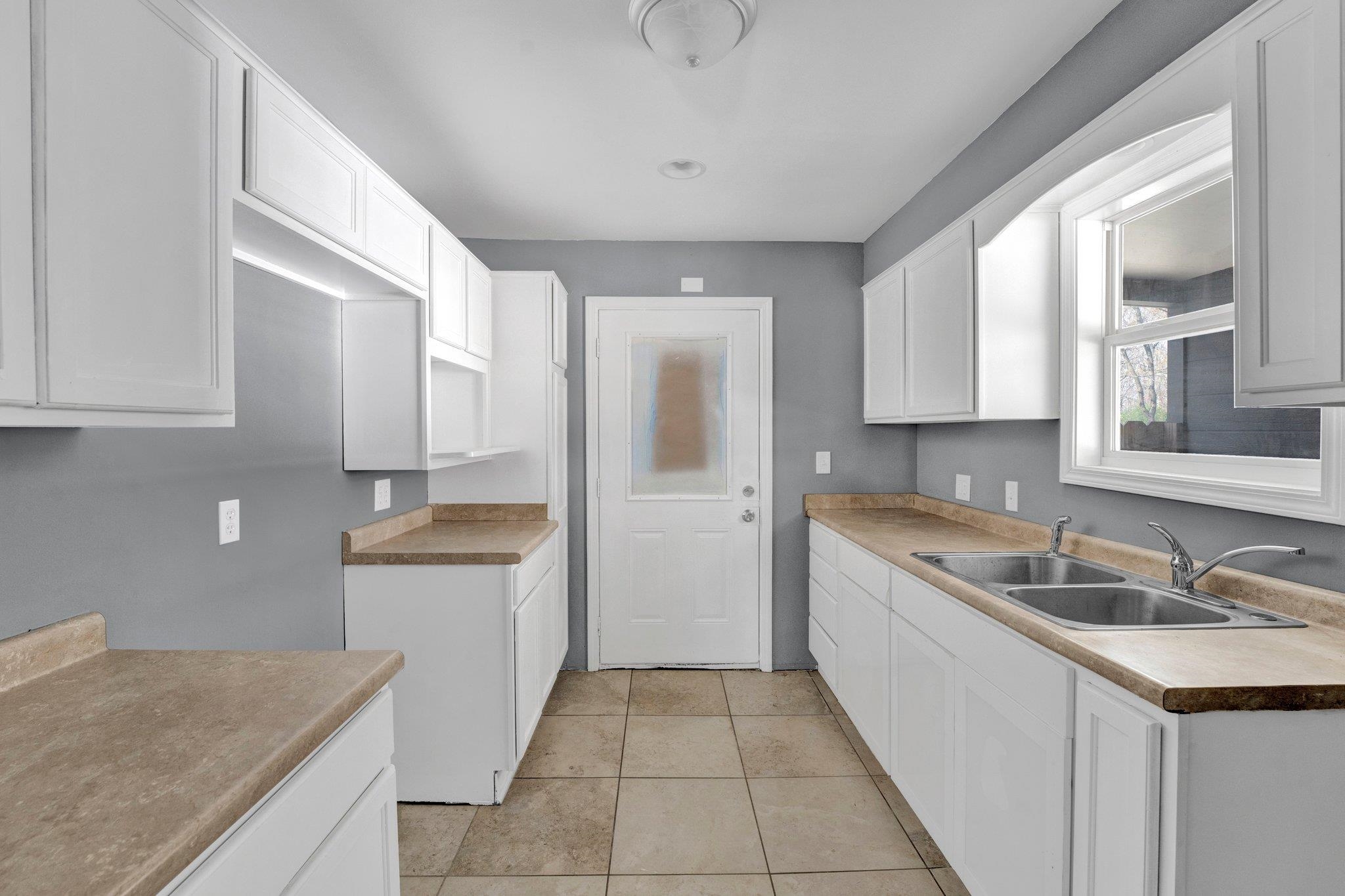 2161 Charjean Road Memphis, TN 38114 - Photo 5 of 18 Kitchen featuring light tile patterned flooring, white cabinetry, and sink