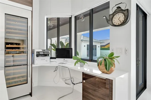 a work place with a desk a clock and a window