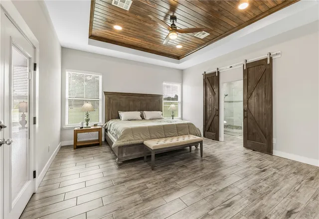 a bedroom with a bed and a large window with wooden floor