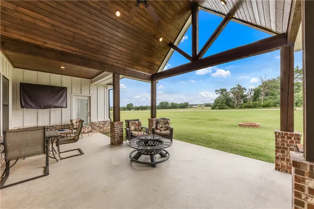 a view of a patio with table and chairs under an umbrella next to a yard