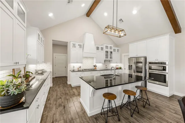 a kitchen with stainless steel appliances granite countertop a stove refrigerator and a dining table with wooden floor