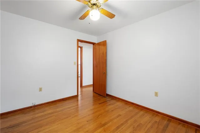 an empty room with a window and ceiling fan