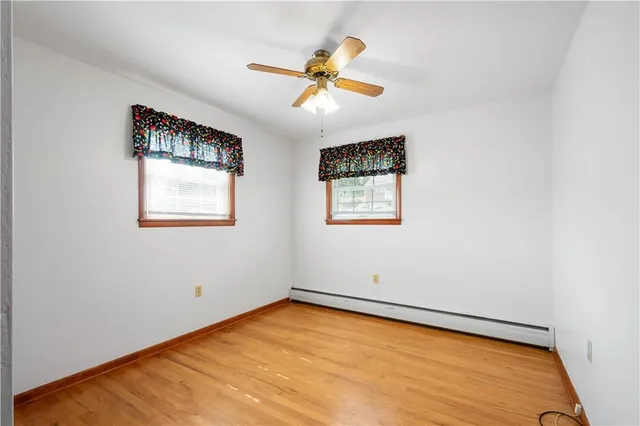 an empty room with wooden floor closet and fan