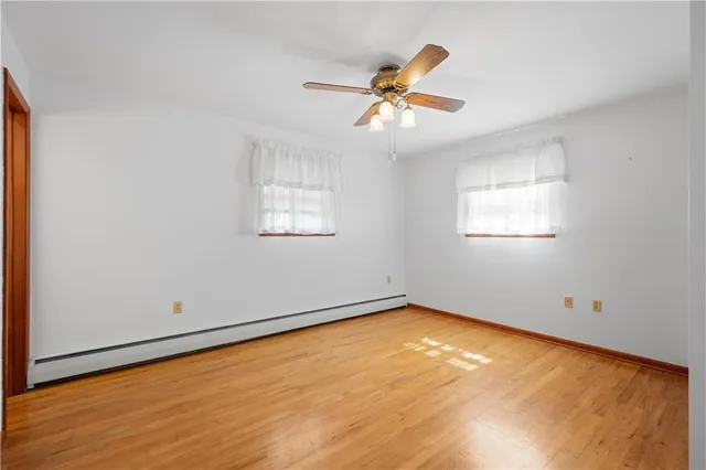 a view of an empty room with wooden floor and a ceiling fan