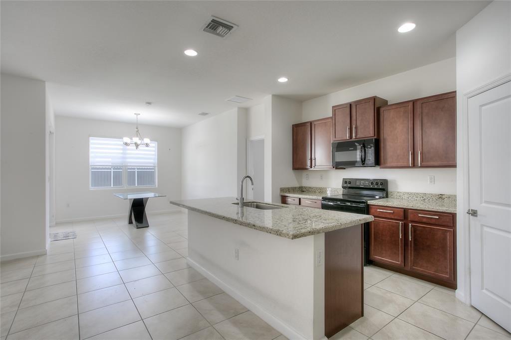 27775 Southwest 133rd Path Homestead, FL 33032 - Photo 7 of 16 a kitchen with kitchen island granite countertop a stove sink and cabinets