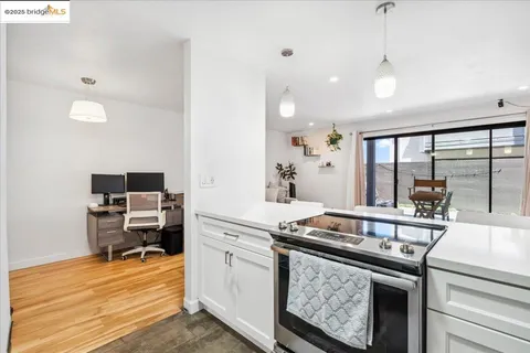 a kitchen with stainless steel appliances granite countertop a stove and a view of living room