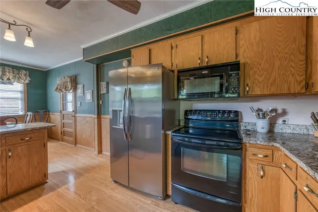 a kitchen with granite countertop a stove top oven microwave and refrigerator