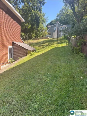 a view of a house with a yard and a large tree