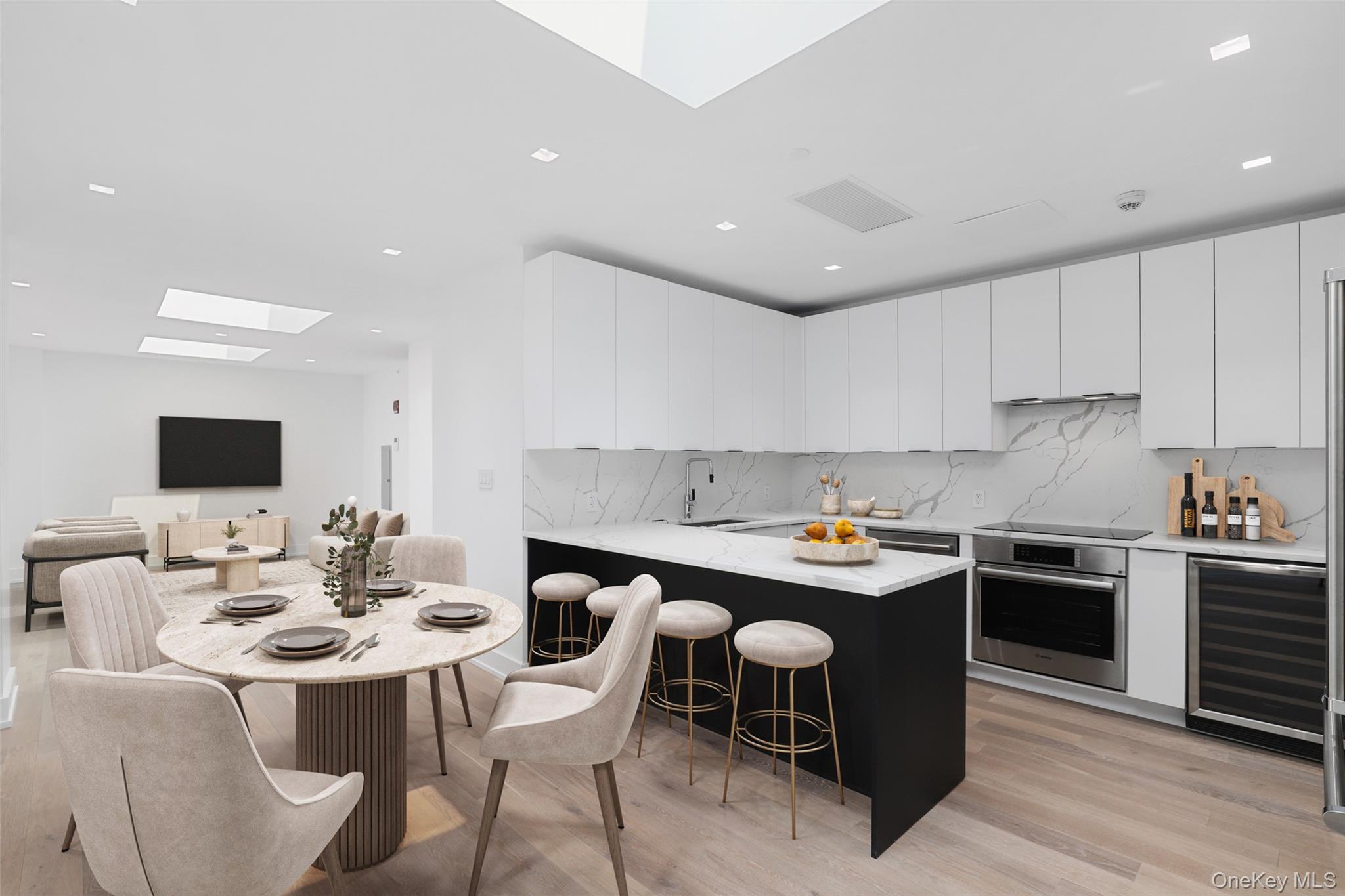 Contemporary kitchen featuring white cabinetry, integrated stainless steel appliances, a center island with counter seating, and light wood-finish flooring