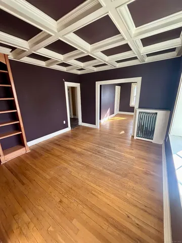 a view of an empty room with wooden floor and cabinet